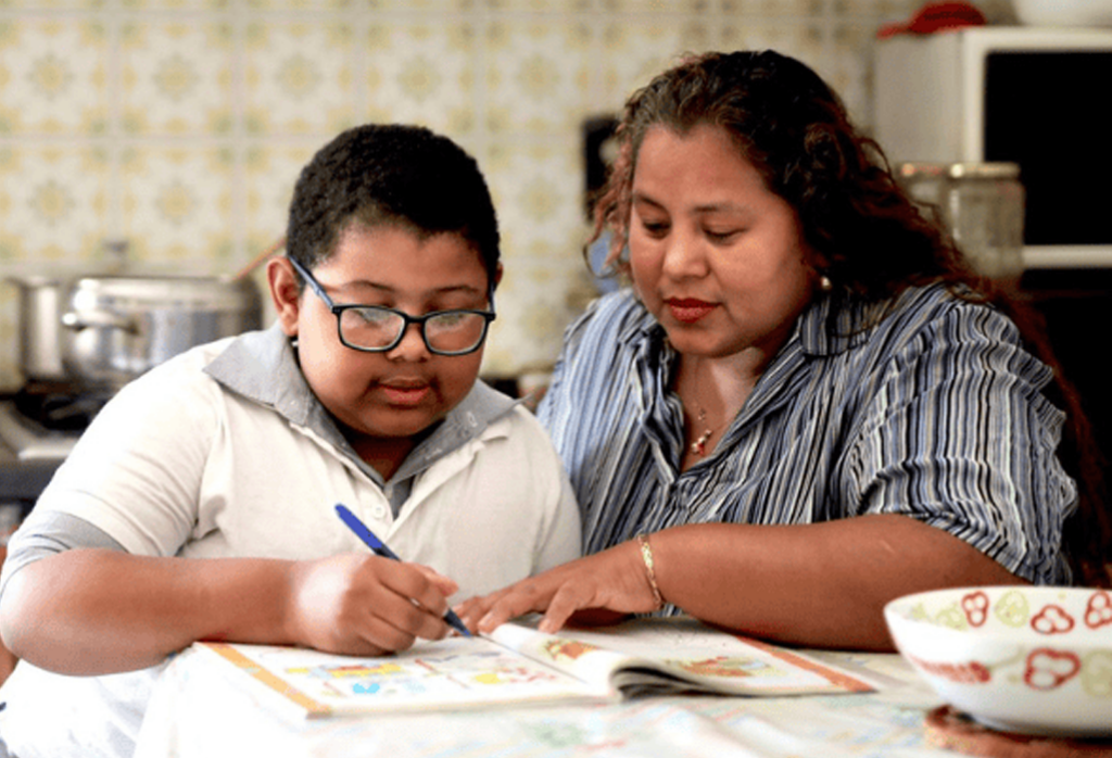 Woman working on homework with her son at the kitchen table.