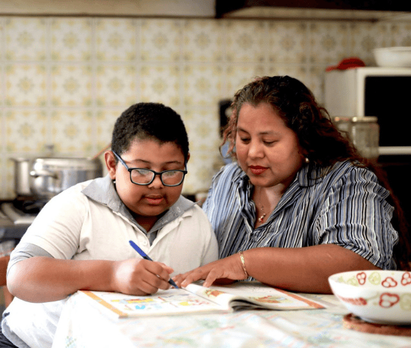 Woman working on homework with her son at the kitchen table.